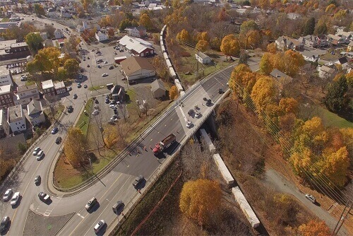 Aerial view of cars and trucks on bridge over train.